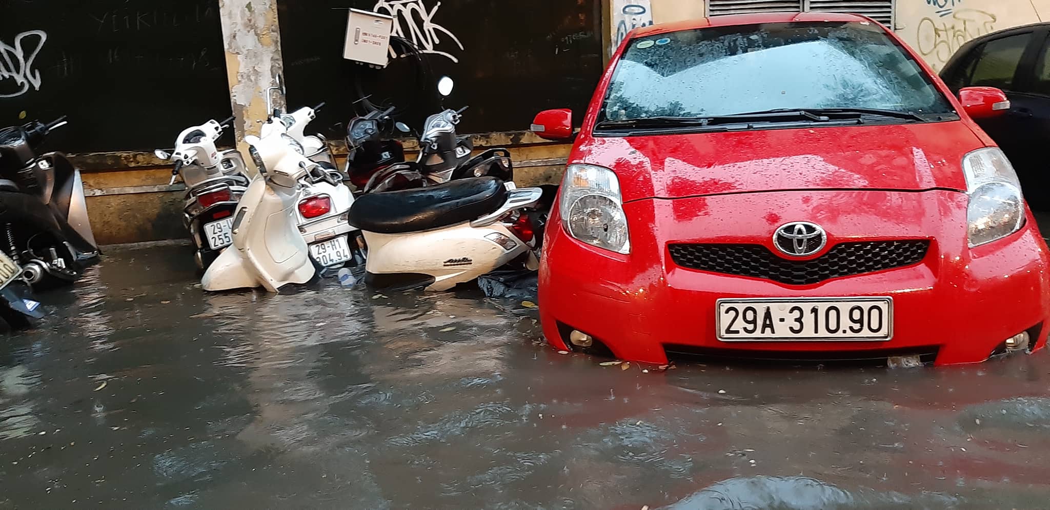 &nbsp;Nhiều ô tô, xe máy để trên vỉa hè cũng bị ngập sâu trong nước. Ảnh Lê Phú.
