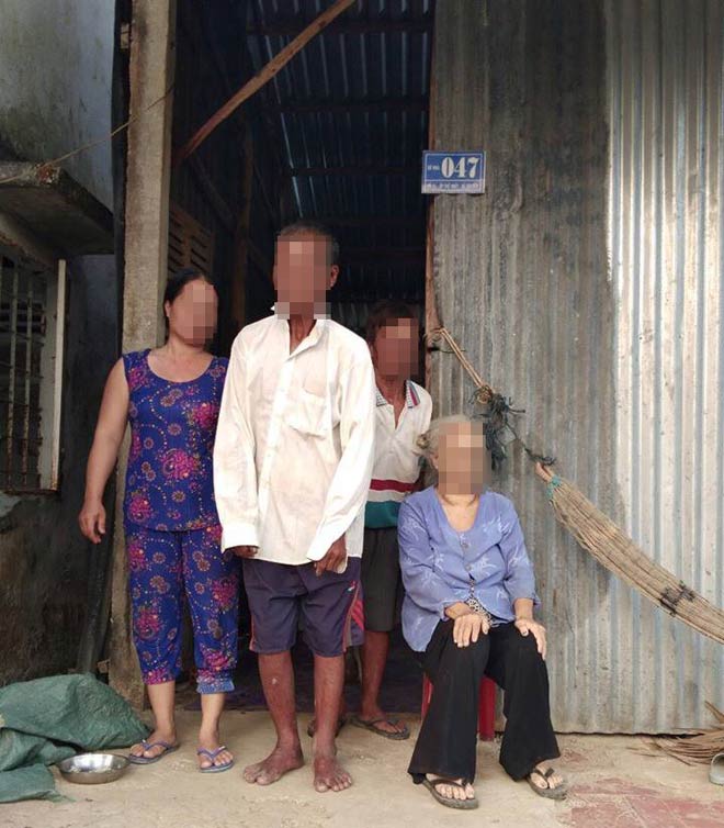 Nương và người thân đứng trước ngôi nhà nghèo nàn.