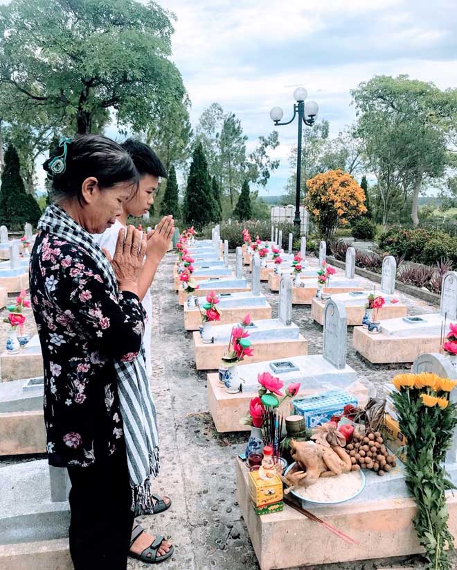 Mẹ chị Huỳnh Thanh Bình và con trai của chị Bình thắp hương tại mộ của ba chị ở Nghĩa trang Đường 9. (Ảnh: NVCC)