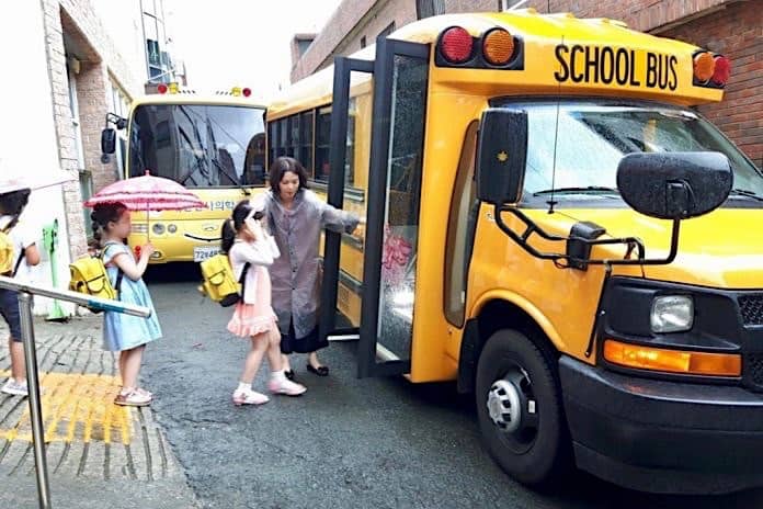 Một giáo viên Hàn Quốc đang đưa các học sinh lên xe buýt của nhà trường