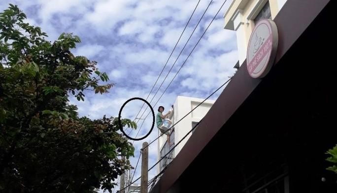 Thợ thi công đã dùng dây buộc... 3 đường dây trung thế lại để sơn vôi mặt tiền công trình