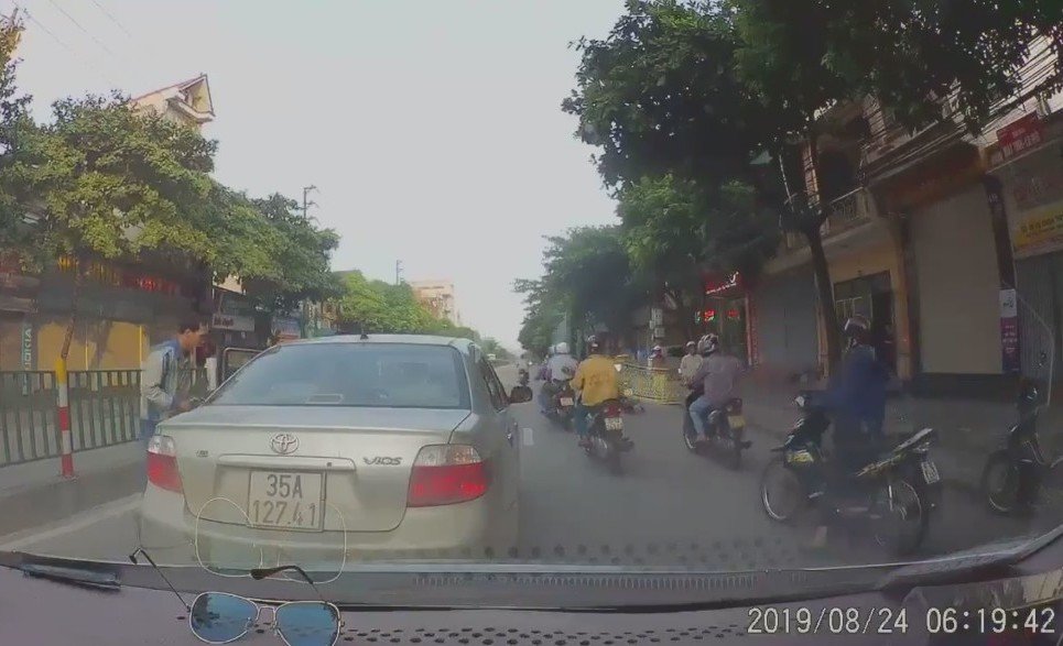 Hình ảnh chiếc xe ô tô con cùng nhiều xe máy dừng lại đột ngột trên đường để nhặt tiền (Ảnh cắt từ clip)