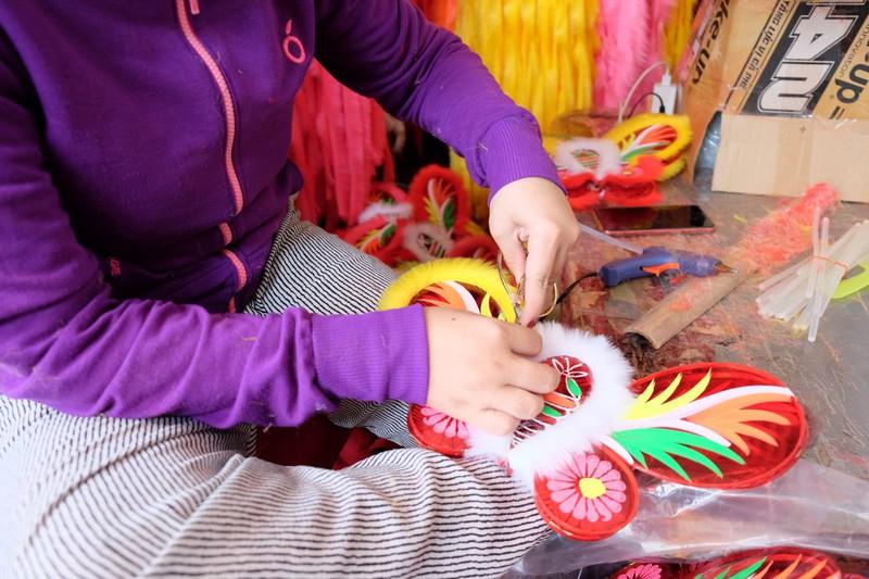 Một nhân công đang hoàn thiện bước cuối cùng của một lồng đèn truyền thống. Ảnh: THU HÀ
