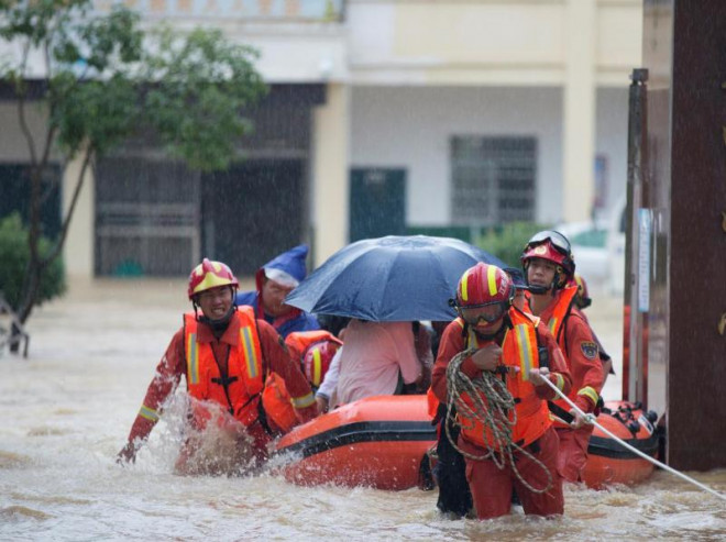 Nhân viên cứu hộ sơ tán học sinh với thuyền bơm hơi bị mắc kẹt bởi nước lũ tại một trường học. Ảnh: REUTERS