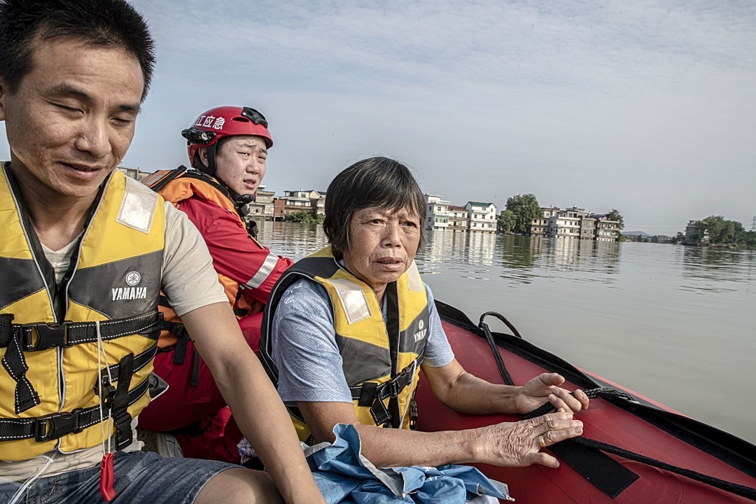 Bà Zhang Meifeng cùng con rể trở lại nhà bằng thuyền cứu hộ (ảnh: LA Times)
