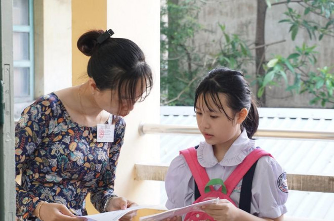 Giám thị kiểm tra giấy tờ của thí sinh trước khi vào phòng thi. Ảnh: NQ