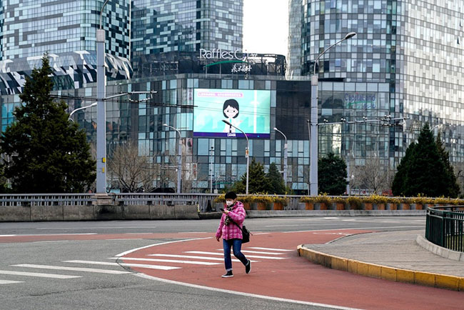 Bắc Kinh: Một người phụ nữ bịt khẩu trang kín mặt khi đi bộ trên con đường vô cùng vắng vẻ.
