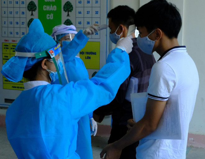 Nhân viên y tế đo thân nhiệt các thí sinh đến làm thủ tục dự thi tốt nghiệp THPT Quốc gia 2020 tại Quảng Ngãi. Ảnh: T.Trực