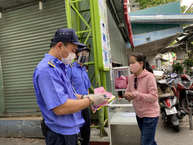 Người dân vào chợ Cồn - Đà Nẵng được kiểm tra qua chốt bảo vệ ở cổng chính. Ở đây bố trí hơn 5 người vừa kiểm tra phiếu, đo thân nhiệt, hướng dẫn người dân điền thông tin vào phiếu