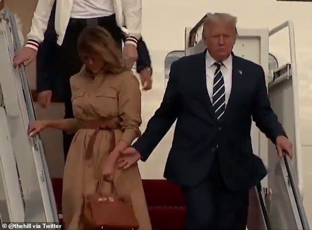 Tổng thống Donald Trump cố nắm tay Đệ nhất phu nhân Mỹ Melania Trump khi bước xuống bậc thang của chuyên cơ Không Lực Một. Ảnh: The Hill