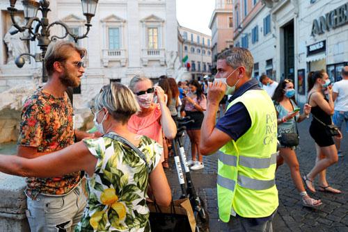 Một cảnh sát khuyên người dân đeo khẩu trang tại TP Rome - Ý gần đây Ảnh: REUTERS