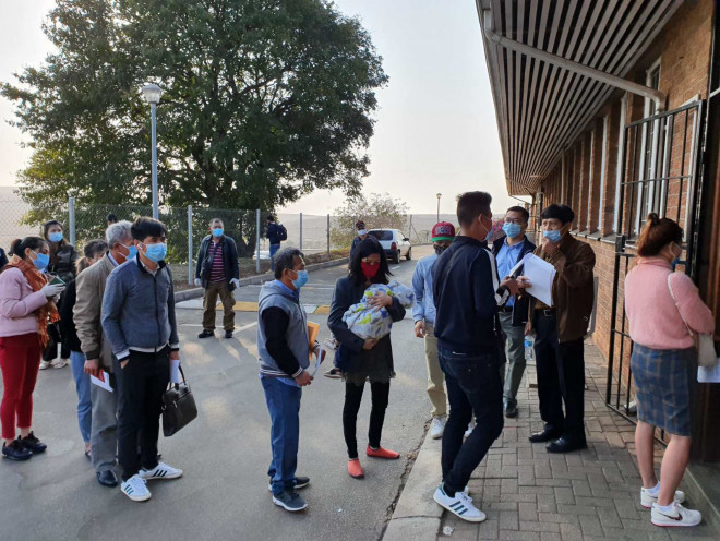 Trời rét, cháu bé dưới 2 tuổi ngủ say trên tay mẹ và đoàn bà con tại Mozambique xếp hàng chờ làm thủ tục xuất nhập cảnh