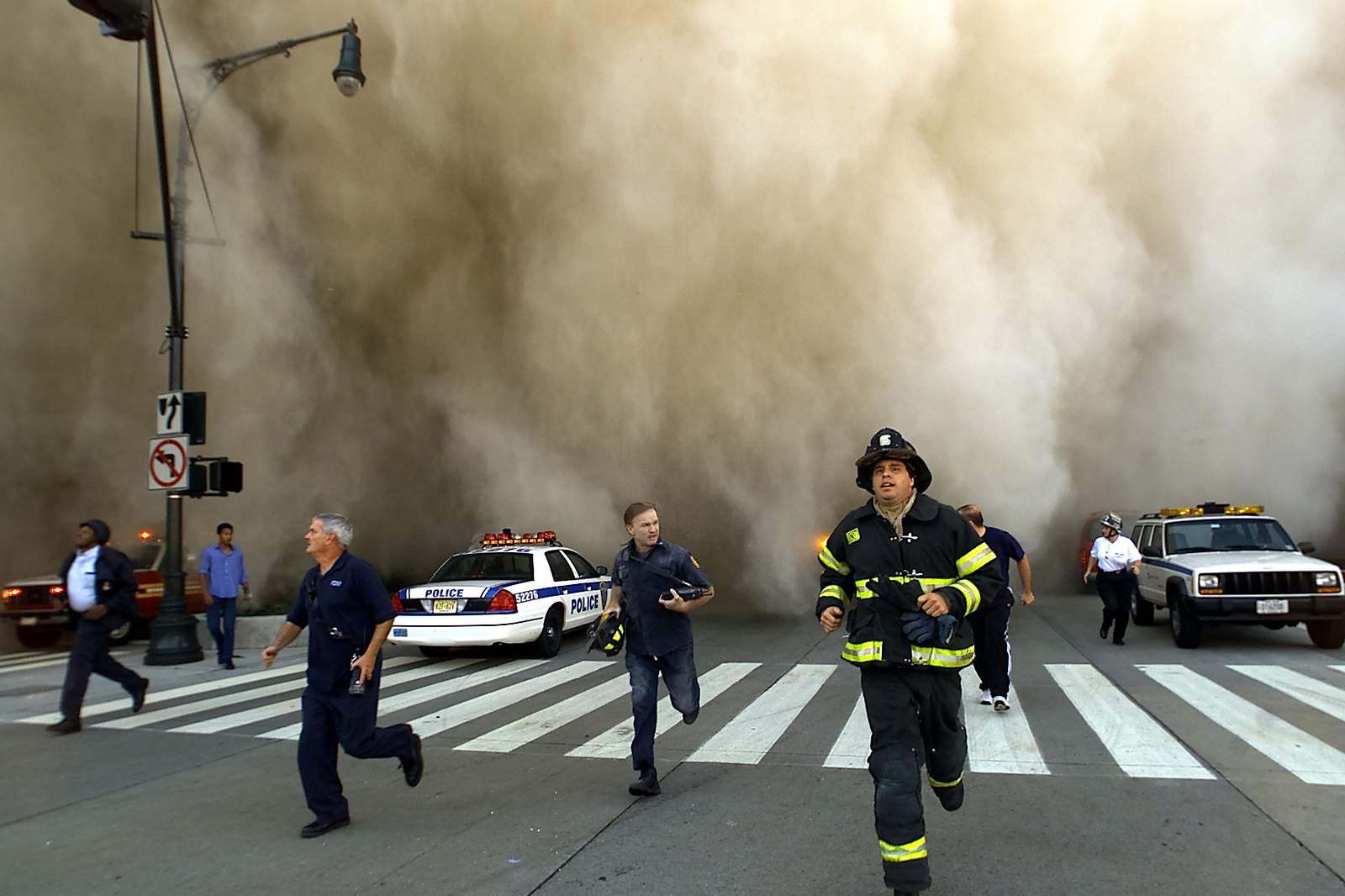 Cảnh sát và lực lượng cứu hỏa bỏ chạy khỏi đám mây bụi khổng lồ khi một trong 2 tòa tháp của WTC sụp đổ
