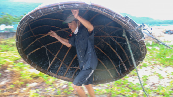 Một ngư dân Đà Nẵng gồng mình gánh thuyền thúng lên bờ để tránh bão số 5. Ảnh: Nguyễn Thành