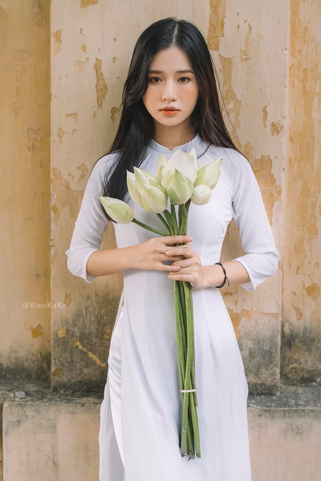 Mai Linh lựa chọn áo dài trắng với thiết kế truyền thống kết hợp thêm với phụ kiện là hoa sen và nón lá. 
