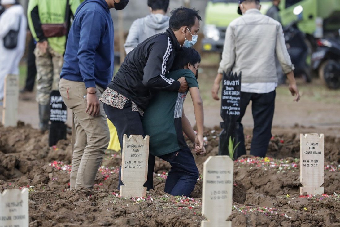 Người thân đứng bên mộ bệnh nhân tử vong vì Covid-19 ở Jakarta, Indonesia.