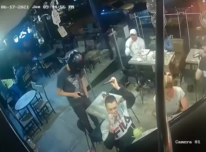 Người đàn ông đưa điện thoại cho tên cướp trong khi vẫn mải ăn cánh gà.