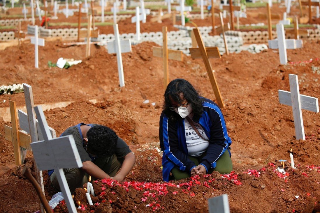 Một phụ nữ và cậu bé cầu nguyện bên mộ người thân tại khu vực chôn cất nạn nhân Covid-19 ở ngoại ô thủ đô Jakarta, Indonesia.&nbsp;Ảnh: Reuters