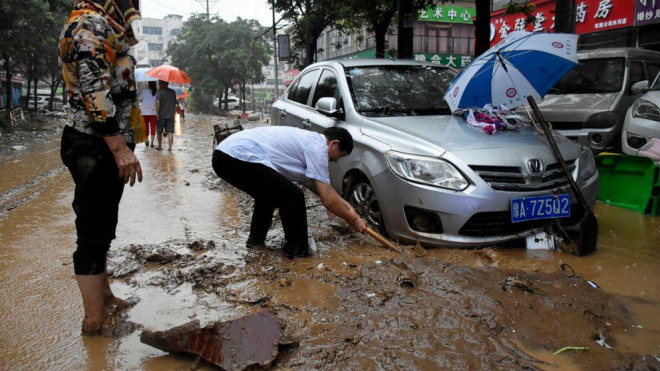 Người dân ở Củng Nghĩa, tỉnh Hà Nam kéo một chiếc xe hơi lên khỏi lớp bùn hôm 21-7. Ảnh: Tân Hoa Xã
