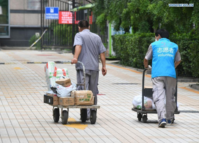 Tình nguyện viên giao nhu yếu phẩm cho người bị cách ly ở thủ đô Bắc Kinh hôm 3-8. Ảnh: Tân Hoa Xã