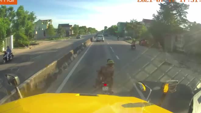 Hai thanh niên đi xe máy không đội mũ bảo hiểm di chuyển chậm cản trở xe container.