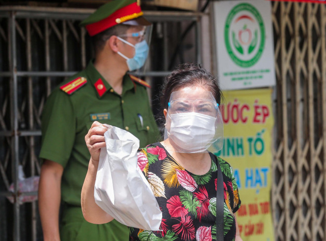 Một người dân khi ra khỏi nhà để nhận nhu yếu phẩm sử dụng kính chống giọt bắn
