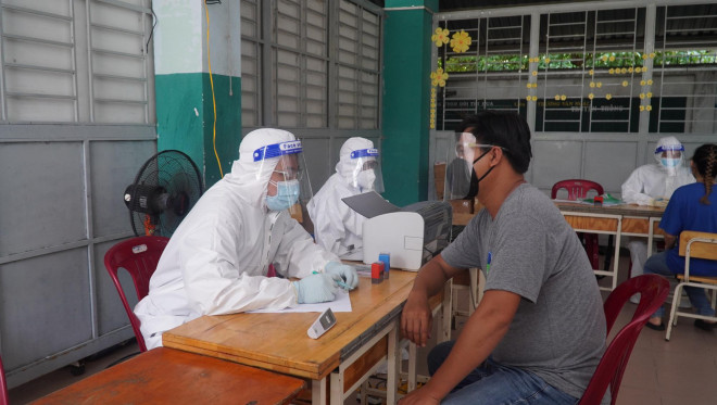 Nhân viên y tế thăm khám cho người dân trước khi tiêm vắc-xin Ảnh: Huế Xuân
