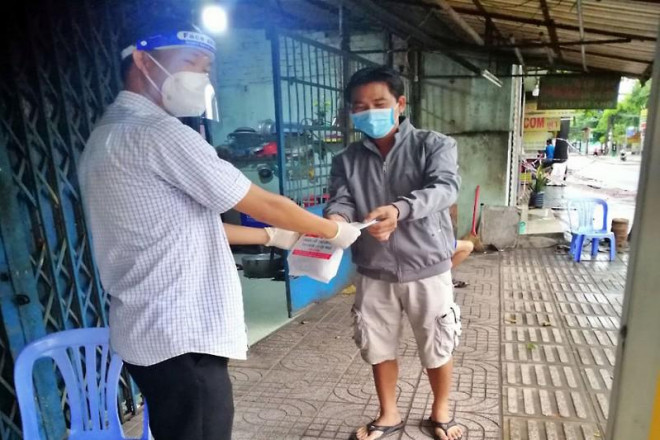 Anh Nguyễn Ngọc Lâm, cán bộ LĐ-TB&amp;XH phường Tân Tạo, quận Bình Tân, đưa thuốc và dặn dò F0 cố gắng điều trị bệnh. Ảnh: NL
