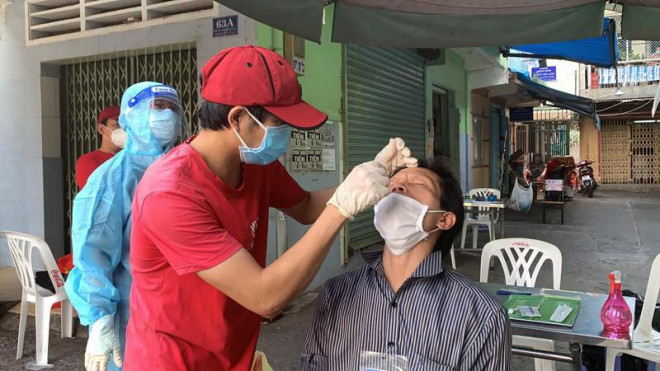 Người dân ở vùng cam ở quận 3 được hướng dẫn tự thực hiện test nhanh cho người thân. Ảnh: HL