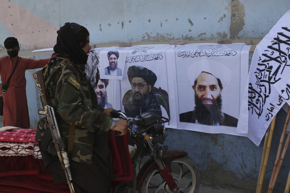 Một tay súng Taliban nhìn vào các tấm poster in ảnh chân dung các thủ lĩnh của tổ chức.