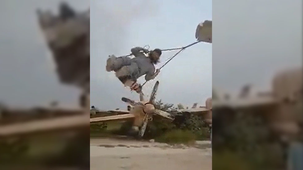 Các tay súng Taliban chơi xích đu móc vào phần cánh một xác máy bay quân sự.