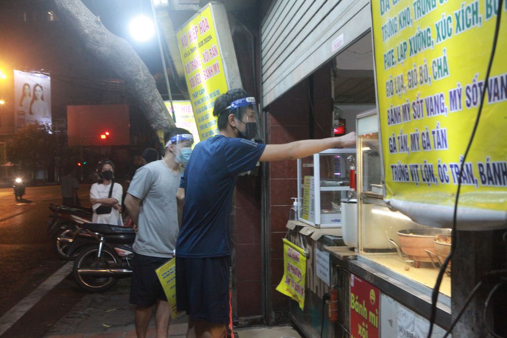 Các quán ăn đêm trên đường Đê La Thành đồng loạt mở cửa trở lại. Một quán bán xôi, gà tần, giò, chả, bánh mỳ… khách cũng phải xếp hàng chờ chủ quán làm
