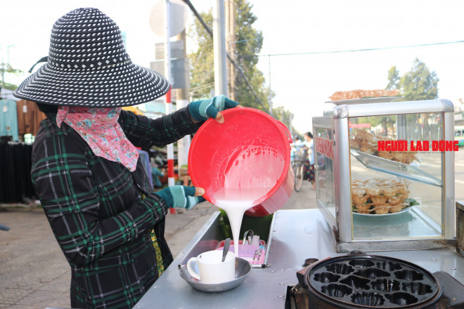 Bà Dân đang rót bột bánh ra chiếc ca để chuẩn bị nướng bánh