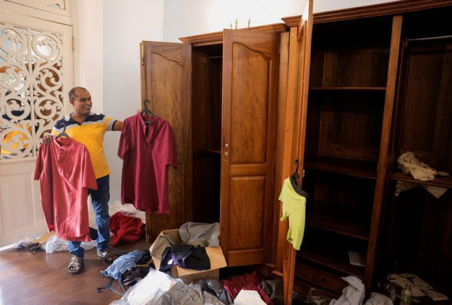 Một người dân cầm trên tay những
chiếc áo sơ mi của Tổng thống Gotabaya Rajapaksa bên trong dinh
thự