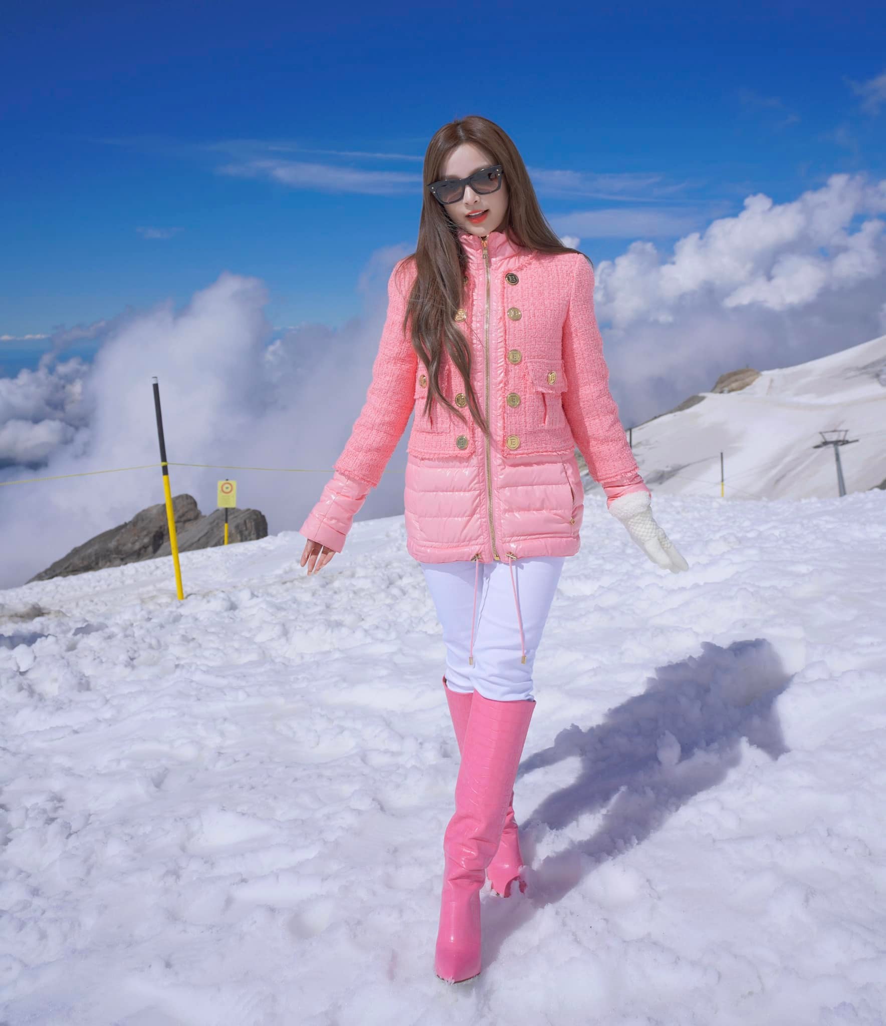 Huyền Baby diện set đồ màu hồng nổi bật, đeo túi xách của Chanel chụp ảnh trên núi tuyết ở Thụy Sĩ. Màu hồng giúp người diện nổi bật hơn giữa không gian màu trắng là chủ đạo.