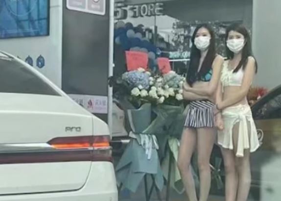 Các cô gái mặc bikini đứng ở trước cửa hàng xăng dầu.