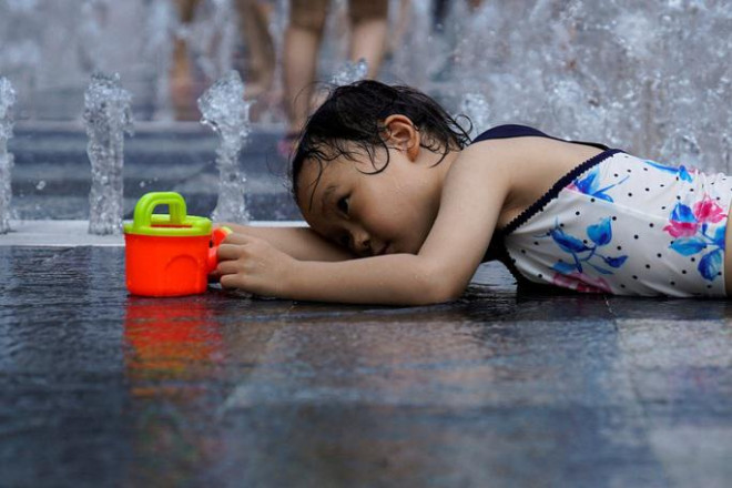 Bé gái nằm bên đài phun nước để tránh nắng nóng tại TP Thượng Hải - Trung Quốc hồi cuối tuần rồi Ảnh: REUTERS