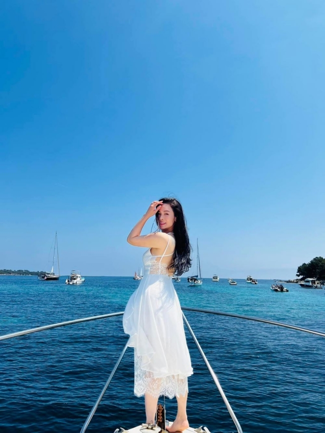 Nhật Kim Anh diện bộ váy trắng nổi bật giữa nền biển xanh. 
