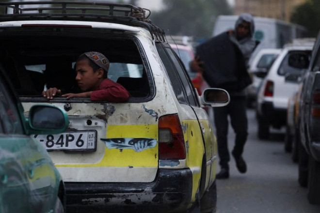 Cậu bé người Afghanistan ngồi sau
chiếc xe hơi đang di chuyển trên đường phố