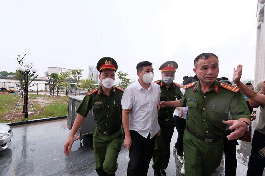 Cựu đại tá Phùng Anh Lê mặc áo trắng, không bị còng tay được đưa đến phiên toà.