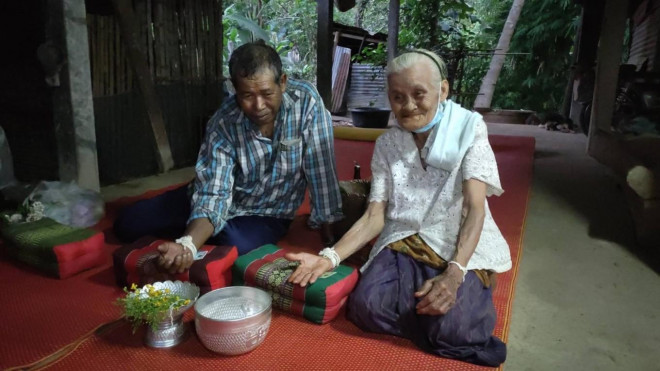 Cặp đôi thực hiện nghi thức buộc chỉ tay theo truyền thống. Ảnh Sanook
