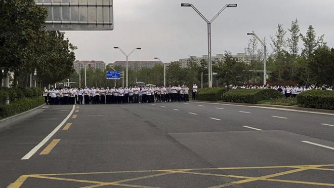 Nhân viên an ninh mặc thường phục đứng trên đường khi người biểu tình đứng trước lối vào chi nhánh của Ngân hàng trung ương Trung Quốc ở Trịnh Châu, tỉnh Hà Nam, vào ngày 10-7. Ảnh: AP