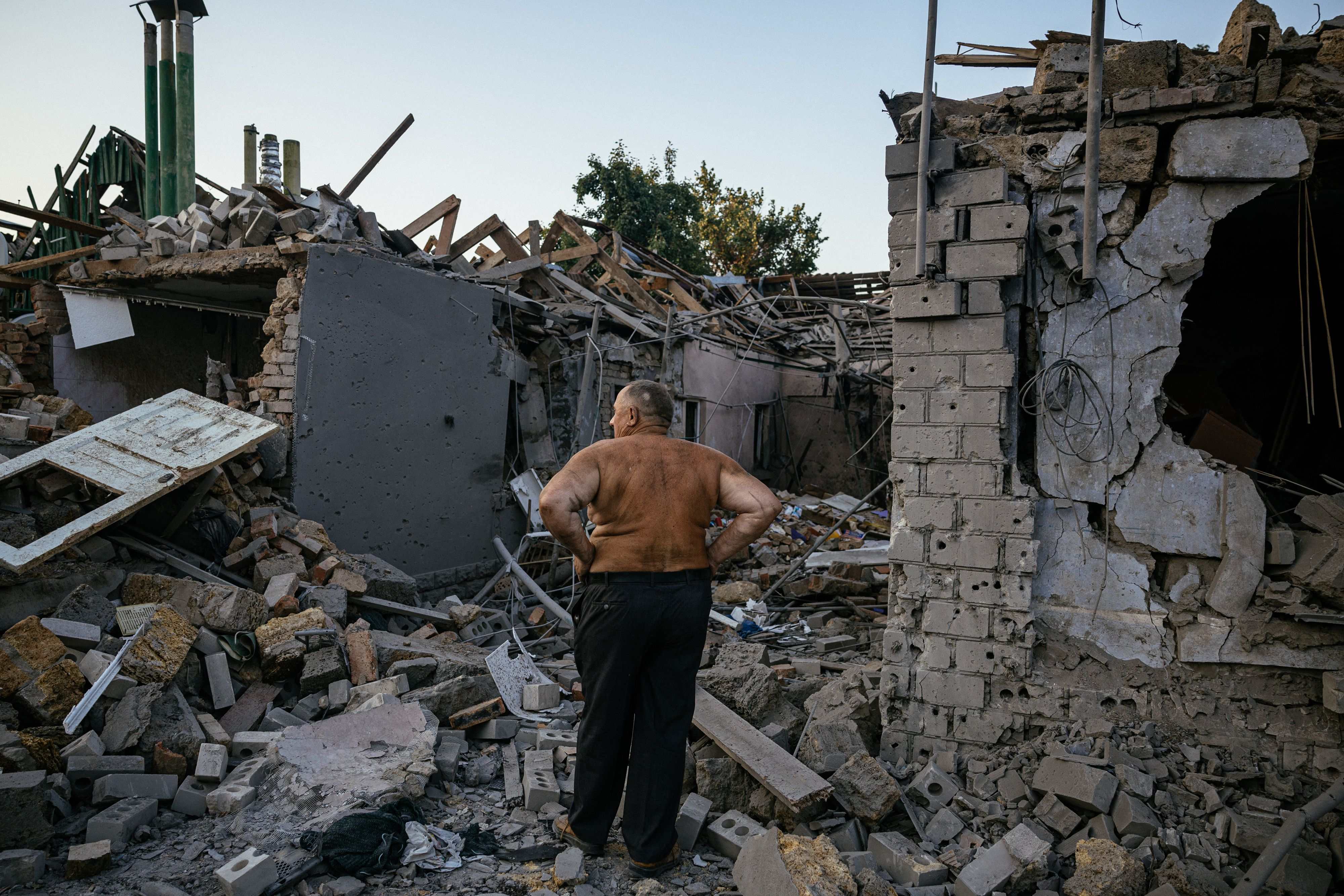 Một người dân đứng trước ngôi nhà bị phá hủy do giao tranh ở miền nam Ukraine (ảnh: CNN)