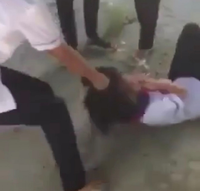 Mặc cho K.A. đau đớn nhưng nữ sinh vẫn bị bạn túm tóc kéo lê trên vỉa hè. Ảnh cắt từ clip.