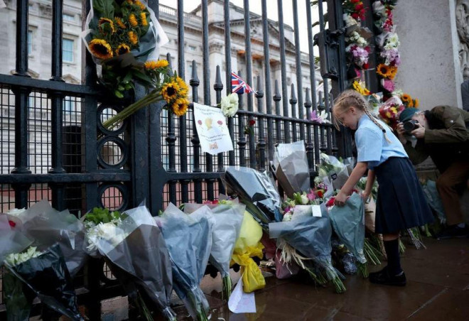 Người dân đặt hoa viếng nữ hoàng bên ngoài cung điện Buckingham. Ảnh: REUTERS