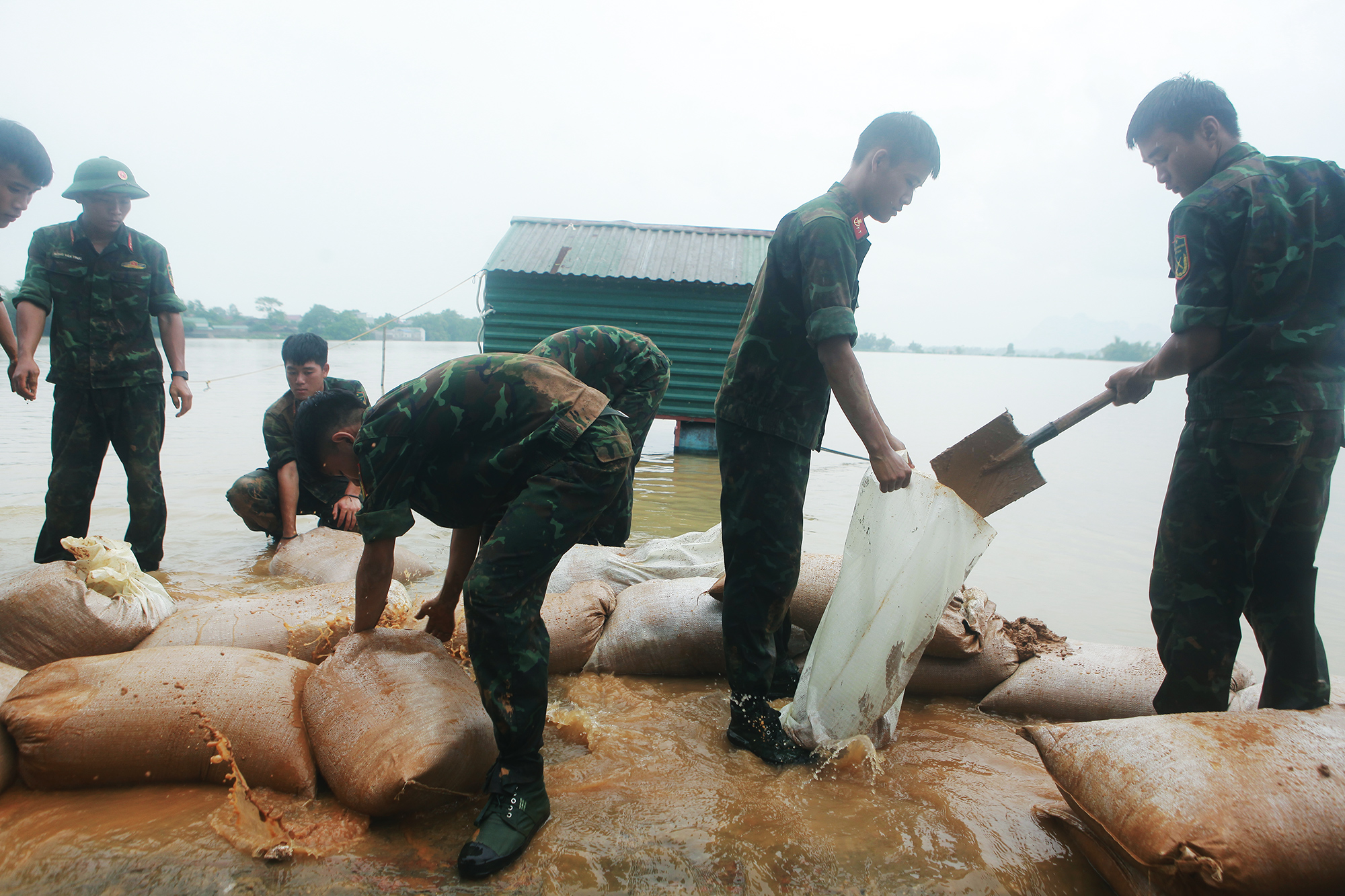 Người dân cùng với lực lượng chức năng, nòng cốt là bộ đội xúc đất, vận chuyển đến những vị trí bị tràn để ngăn nước