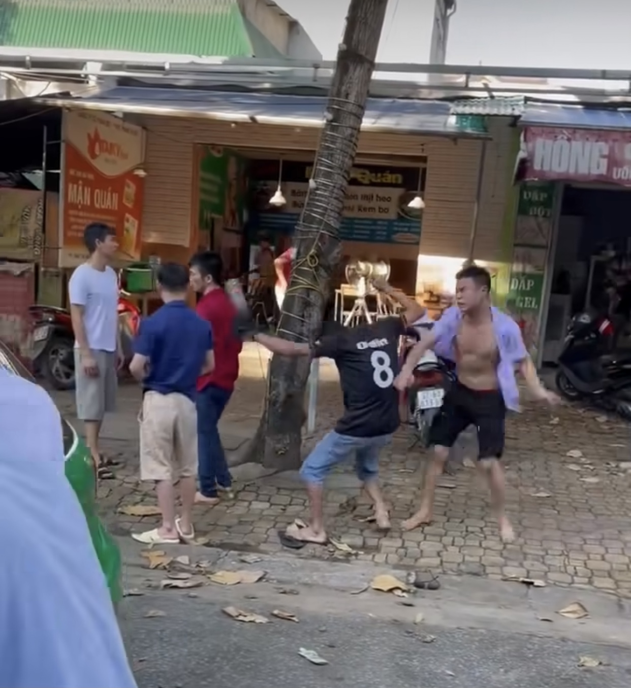 Hai người đàn ông bị gạch văng trúng đầu đều gục ngã ra đường (Ảnh cắt từ clip)