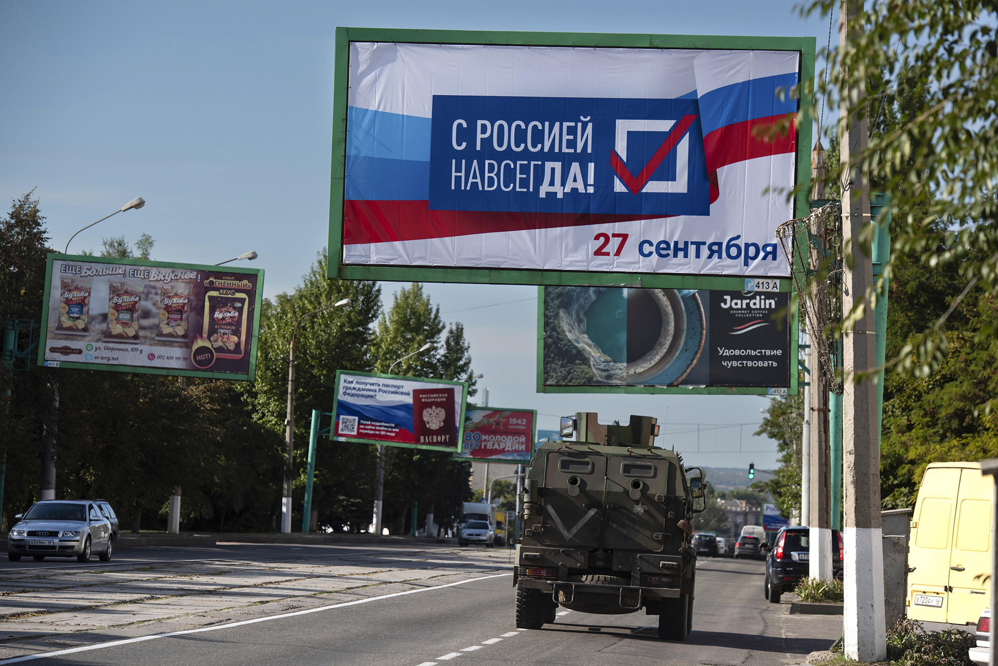 Xe quân sự Nga đi qua một tấm biểu kêu gọi người dân tham gia trưng cầu dân ý ở Lugansk (ảnh: Reuters)