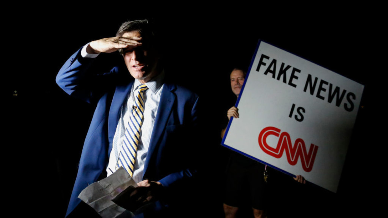 Một người biểu tình giơ biểu ngữ "CNN là hãng tin giả" khi người dẫn chương trình của CNN đưa tin về cuộc đột kích của FBI vào dinh thự của cựu Tổng thống Mỹ Donald Trump.