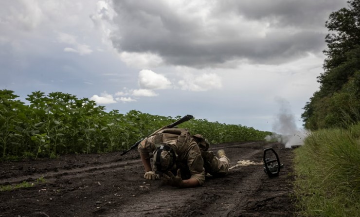 Lính Ukraine nằm xuống chỗ an toàn sau khi gỡ một quả mìn chống tăng. Ảnh: THE WASHINGTON POST